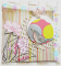 Carte d'amitiés  en scrap oiseau dans son nid de fleurs suspendu sur fond multicolore rose, jaune, fris graphique