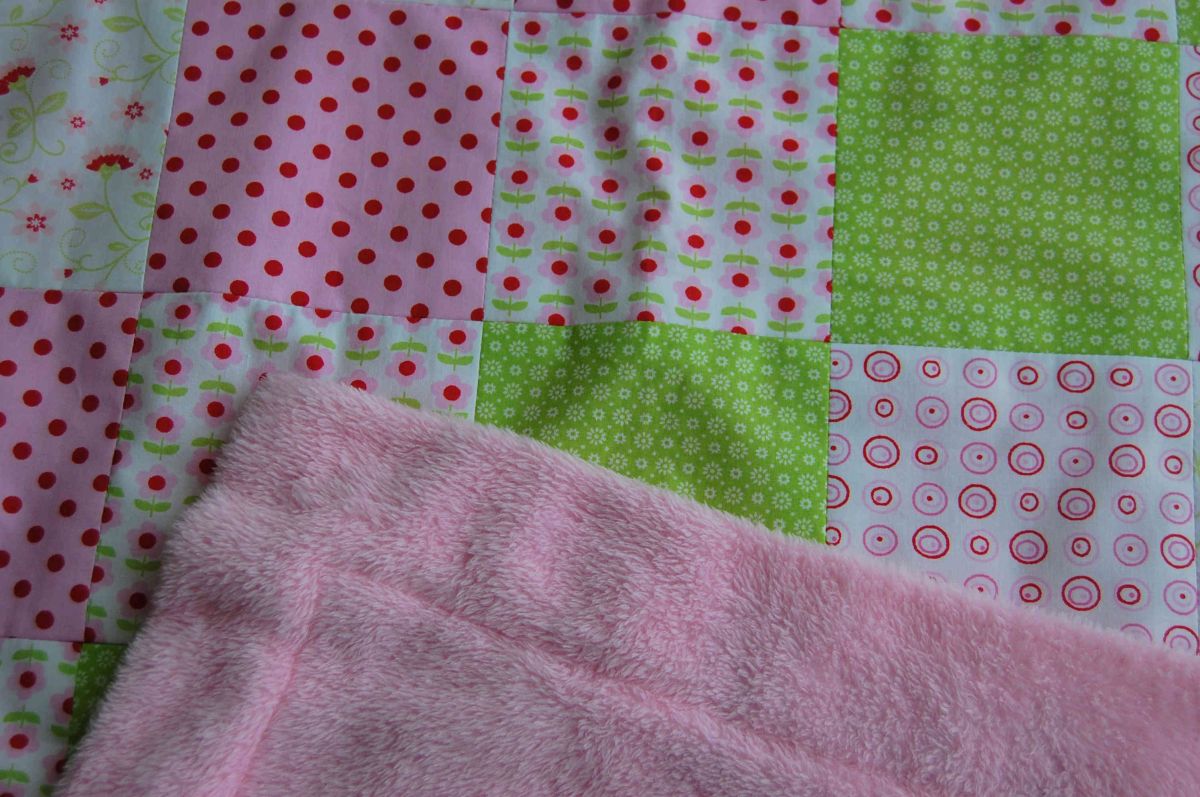Couverture de bébé en polaire rose et patchwork de coton vert, rose, rouge.
