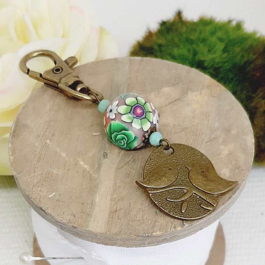 porte clé médaille duo d'oiseaux couleur bronze et perle artisanale motif floral vert et lie de vinmulticolore