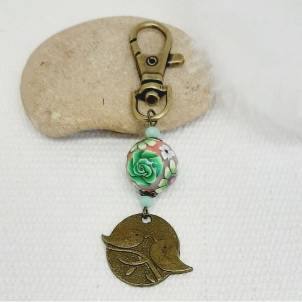 porte clé médaille duo d'oiseaux couleur bronze et perle artisanale motif floral vert et lie de vinmulticolore