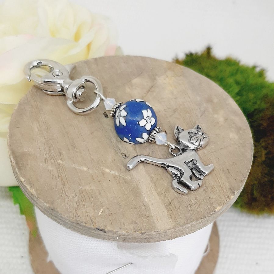 porte clés pendentif argenté chat et perle bleu marine à fleur blanche