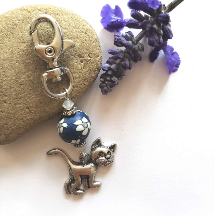 porte clés pendentif argenté chat et perle bleu marine à fleur blanche