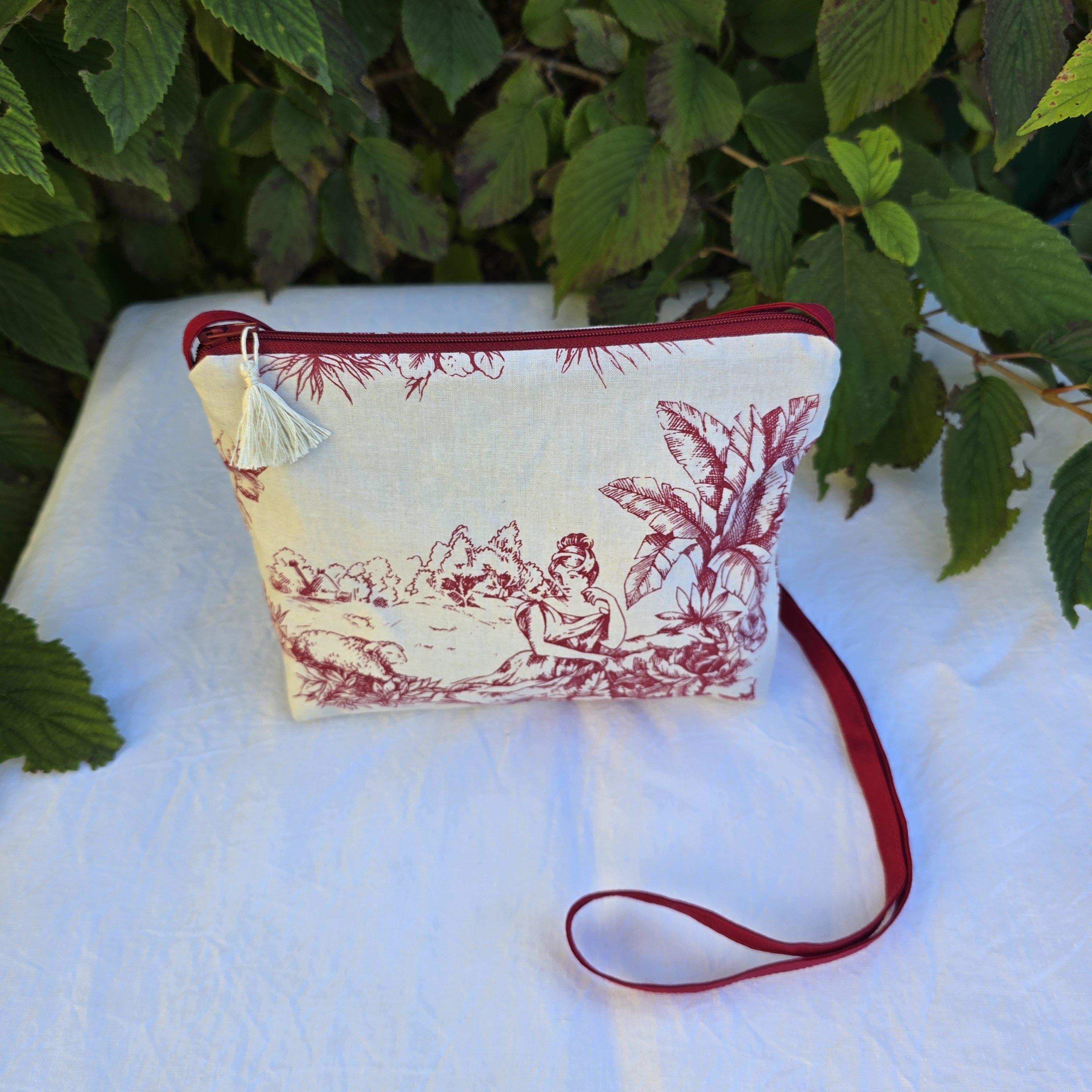 Pochette avec bandoulière en tissu toile de Jouy bordeaux et écru agrémentée d'un pompon