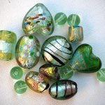 Lot de 12 perles en verre différentes, tons vert foncé avec reflets or