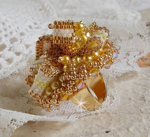 Bague Sunflower Gold brodée d’un ruban que j’ai mis en forme avec des rocailles plaquées or 24 carats, perles nacrées en cristal, toupies, perle ronde nacrée. Le tout est monté sur une bague Dorée