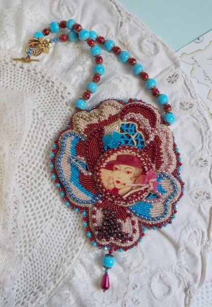 Collier Bel&rsquo;Art brod&eacute; sur une base en su&eacute;dine Bordeaux un cabochon baroque d&rsquo;une femme des ann&eacute;es 1950 en R&eacute;sine &agrave; laquelle s&rsquo;ajoute : perles rondes nacr&eacute;es, chips Grenat, fleurs Lucites et rocailles 