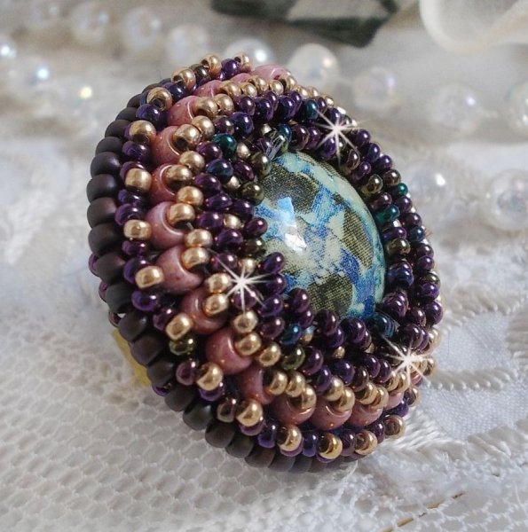 Bague Bonjour Paris cabochon marbr&eacute; bleu/vert/&eacute;cru orn&eacute;e de rocailles Miyuki dont la couleur dominante est le Violet. Mont&eacute;s sur bague dor&eacute;e en laiton et sur une feutrine Bleu n&eacute;on. Un look city !