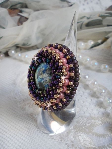 Bague Bonjour Paris cabochon marbr&eacute; bleu/vert/&eacute;cru orn&eacute;e de rocailles Miyuki dont la couleur dominante est le Violet. Mont&eacute;s sur bague dor&eacute;e en laiton et sur une feutrine Bleu n&eacute;on. Un look city !