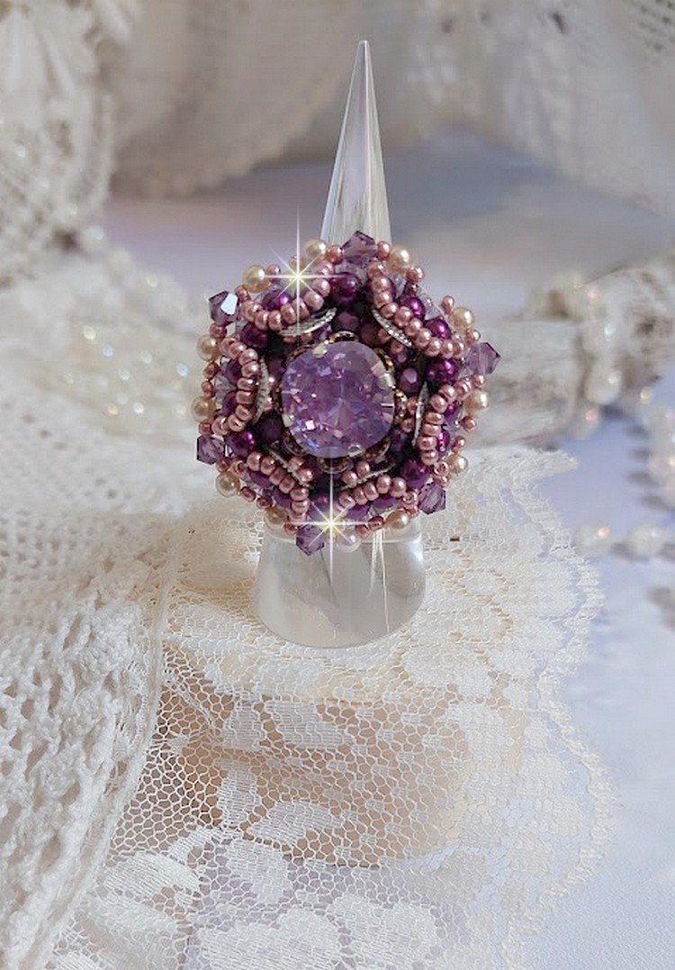 Bague Chinese Purple Stone brodée avec un cabochon rond en cristal Violet à laquelle s'ajoute une grande coupelle filigranée, facettes, perles rondes nacrées et rocailles sur un support bague Argentée