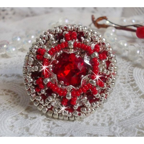 Bague Drigon Red brod&eacute;e avec un cabochon carr&eacute; Rouge sur une estampe Argent&eacute;e. Orn&eacute;e de chatons en Cristal puis model&eacute;e avec des rocailles et perles. Le tout est mont&eacute; sur une bague r&eacute;glable argent&eacute;e 