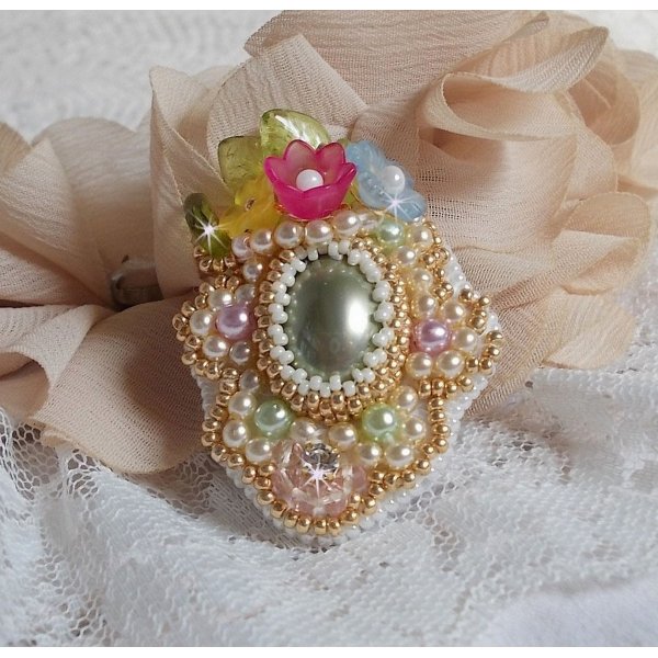 Bague Envol&eacute;e Fleurie brod&eacute;e avec un cabochon ovale Olivine en r&eacute;sine, orn&eacute;e de perles rondes nacr&eacute;es, des rocailles, fleurs Lucites, mini gouttes, chaton en Cristal et perles rondes aplaties.