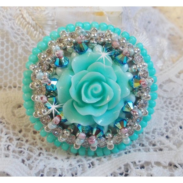 Bague Blue Flowers brod&eacute;e avec un cabochon en forme de rose en r&eacute;sine, cha&icirc;ne strass Cristal, toupies Jet de haute qualit&eacute; AB2X et farfalles ovales. Les couleurs sont : l&rsquo;Argent&eacute; et le Vert Menthe