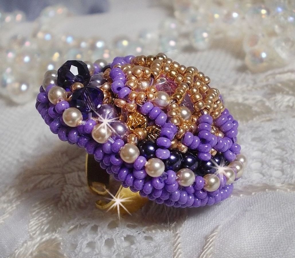 Bague Laureline brodée sur une bague Dorée avec un cabochon carré Violet, perles rondes aplaties, perles rondes nacrées en verre Ivoire, Mauve et Purple, rocailles pour un style Contemporain