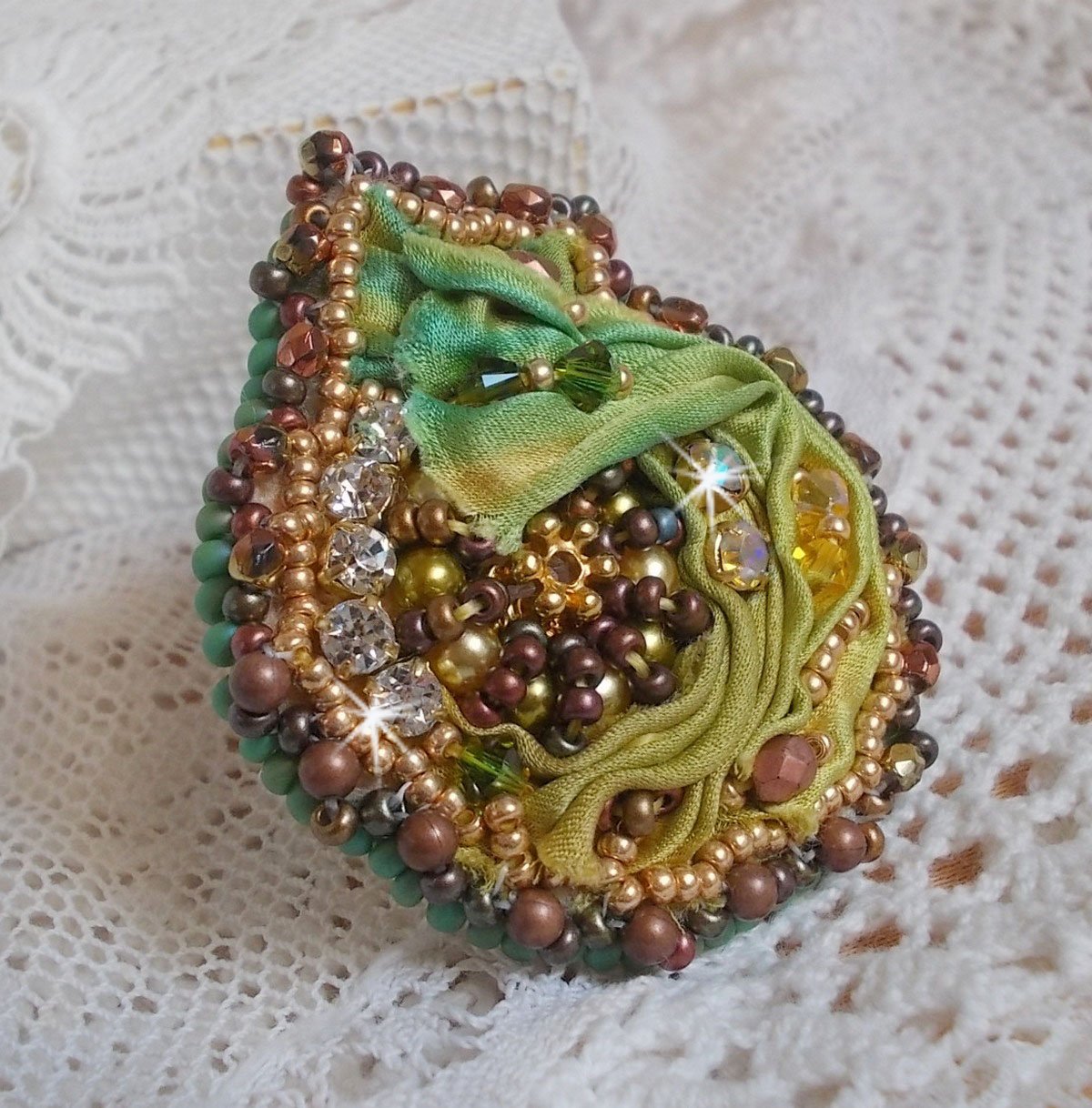 Bague Lune Vénitienne brodée avec un ruban de soie Orange, Vert et Jaune, cristaux : toupies, perles rondes nacrées et chatons. S’ajoute des facettes et rocailles en Verre sur une bague filigranée 