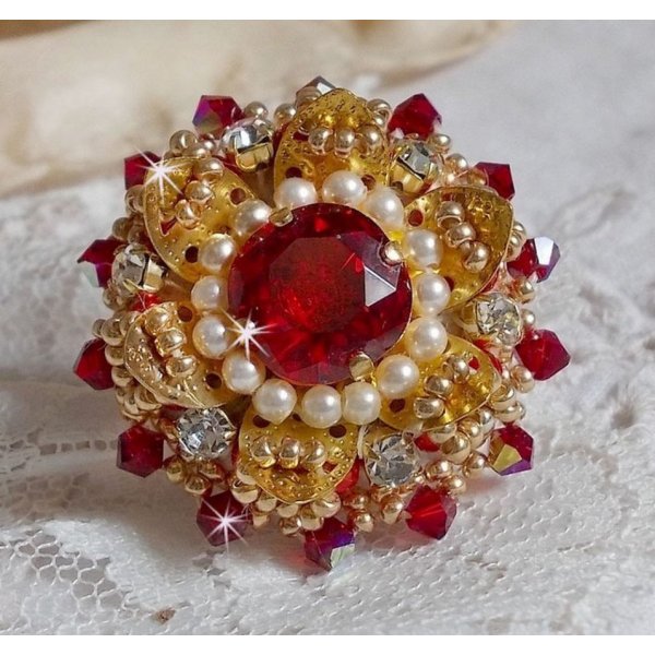Bague L&rsquo;Oiseau des Iles Rouge Dor&eacute; avec un cabochon Rouge sur une estampe dor&eacute;e orn&eacute;e de cristaux : toupies et chatons. Les perles rondes nacr&eacute;es Ivoire et Rouge compl&egrave;tent cette bague r&eacute;glable Dor&eacute;e