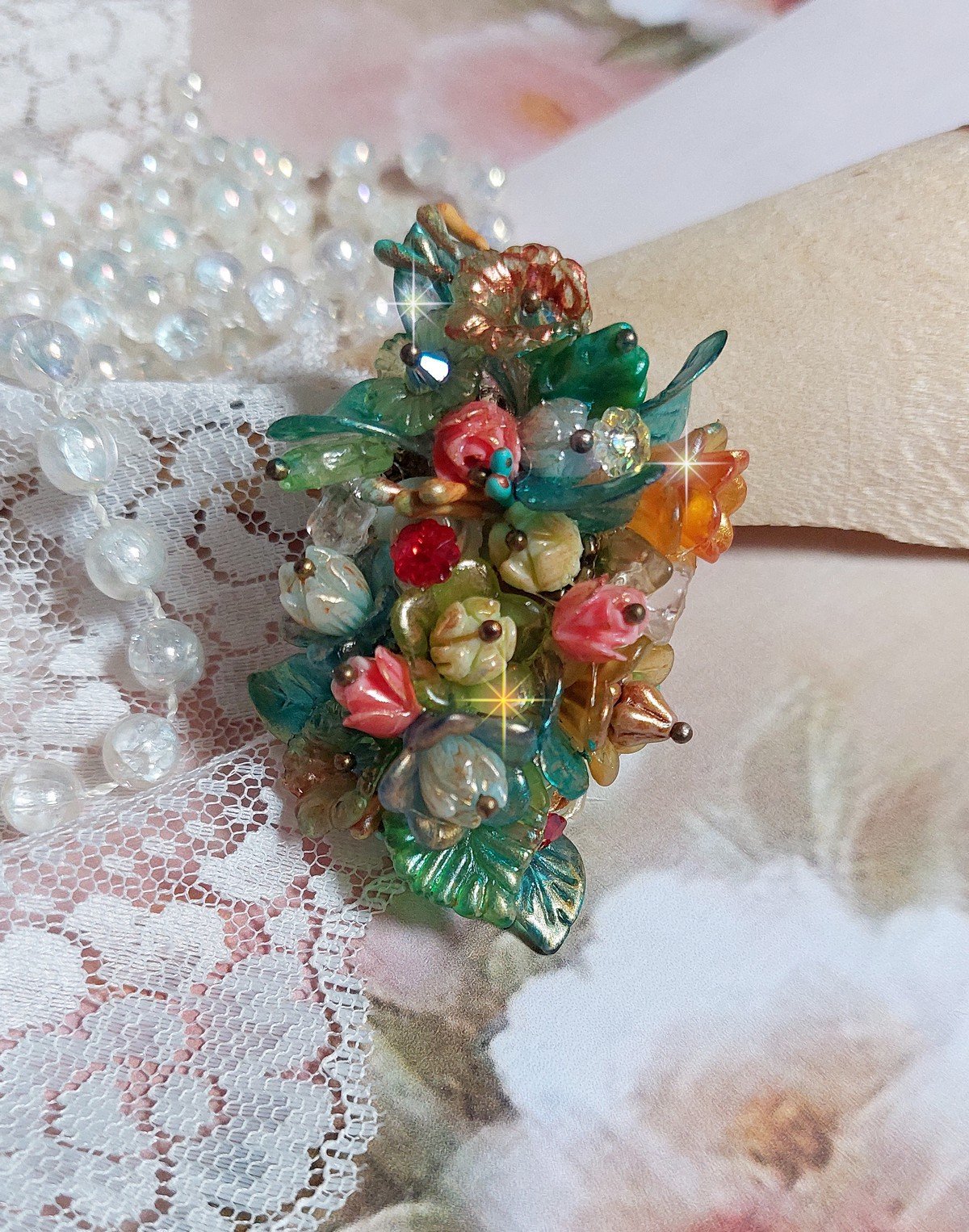 Bague Patiflo d&rsquo;une composition florale cr&eacute;&eacute;e avec des cristaux, fleurs en R&eacute;sine, perles, clochettes, pens&eacute;es, boutons de rose en Verre, estampes et coupelles. Le tout est mont&eacute; sur une bague estampe