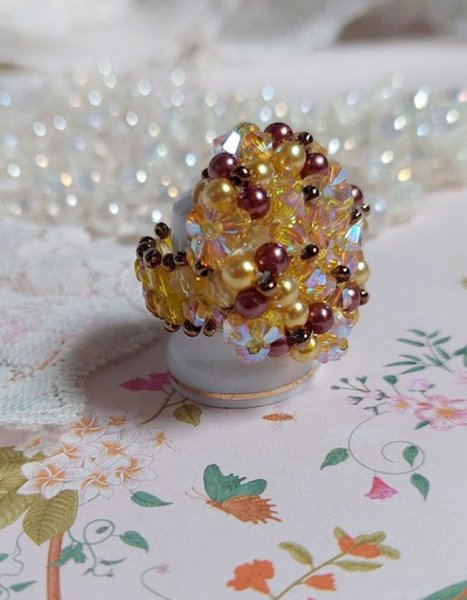 Bague Soleil mont&eacute;e avec des toupies en Cristal de Swarovski aux couleurs Topaze, Gold et Marron &agrave; laquelle s&rsquo;ajoute des facettes en Verre de Boh&egrave;me. Les perles s&rsquo;entrelacent avec les rocailles Dor&eacute;es