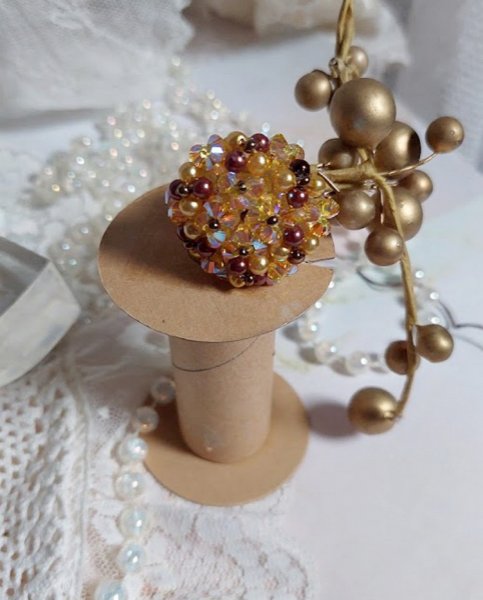 Bague Soleil mont&eacute;e avec des toupies en Cristal de Swarovski aux couleurs Topaze, Gold et Marron &agrave; laquelle s&rsquo;ajoute des facettes en Verre de Boh&egrave;me. Les perles s&rsquo;entrelacent avec les rocailles Dor&eacute;es