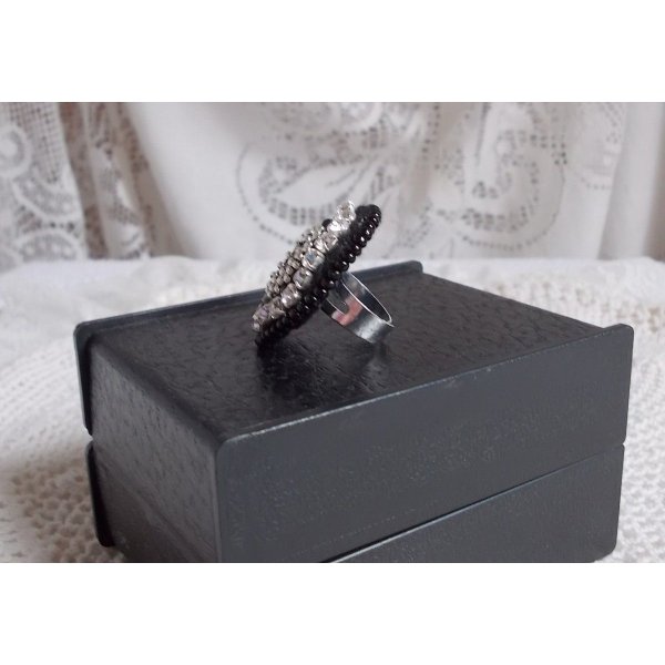 Bague Stone Noire avec un cabochon en Onyx orn&eacute; de chatons en Cristal &agrave; laquelle s&rsquo;ajoute des rocailles Argent&eacute;es qui compl&egrave;tent le Noir sur bague Nickel en Laiton et une feutrine. Un style R&eacute;tro