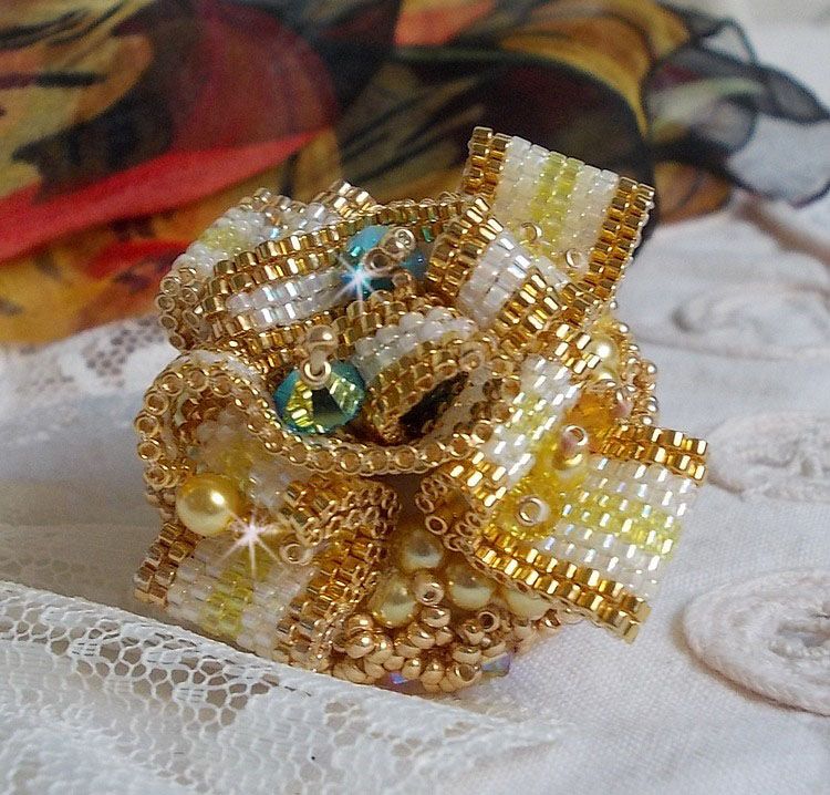 Bague Sunflower Gold brodée d’un ruban que j’ai mis en forme avec des rocailles plaquées or 24 carats, perles nacrées en cristal, toupies, perle ronde nacrée. Le tout est monté sur une bague Dorée