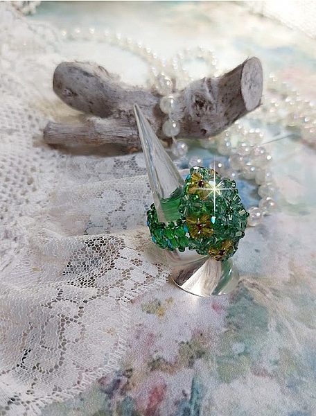 Bague Vert Tendre mont&eacute;e avec des toupies en Cristal dans les nuances de Vert Emerald et Jaune &agrave; laquelle s'ajoute des facettes et des rocailles. Un feuillage verdoyant de fleurs
