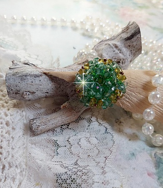 Bague Vert Tendre mont&eacute;e avec des toupies en Cristal dans les nuances de Vert Emerald et Jaune &agrave; laquelle s'ajoute des facettes et des rocailles. Un feuillage verdoyant de fleurs