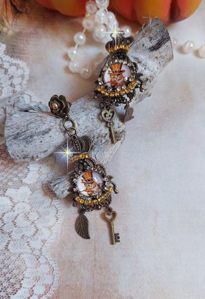 BO Chatibo Steampunk mont&eacute;es avec cabochons ronds en verre repr&eacute;sentant un chat chapeaut&eacute; Haute de Forme Orange. Strass&eacute;es avec une couronne, breloques cl&eacute;s et feuilles. Mont&eacute;es sur clips Bronze