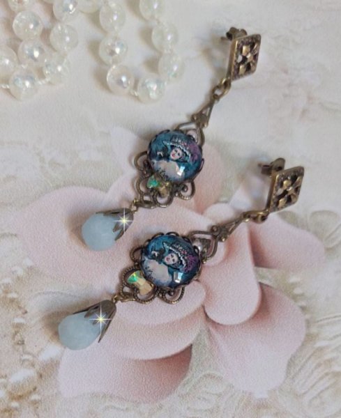 BO Dame au chapeau fleuri repr&eacute;sentant une femme au chapeau entour&eacute; d&rsquo;un ruban noir est mont&eacute; sur des estampes avec des n&oelig;uds en cristal. Une belle &eacute;l&eacute;gance avec ces gouttes en Jade teint&eacute;es de Bleu