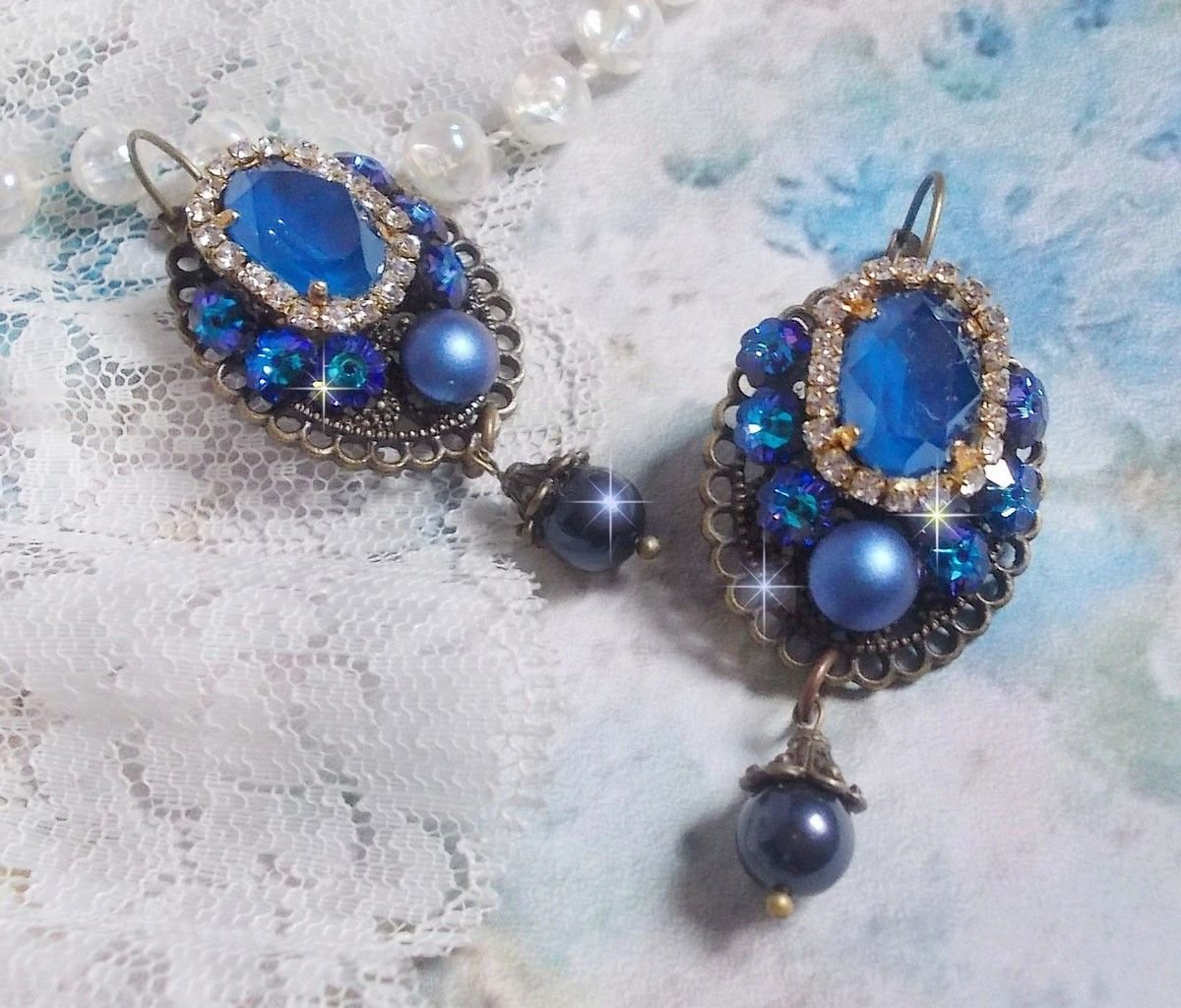 BO Leila avec des cabochons ovales de couleur Royal Blue à laquelle s’ajoute des cabochons ronds, perles nacrées et fleurs. Ils sont tous en Cristal, les dormeuses couleur Bronze sont en Laiton