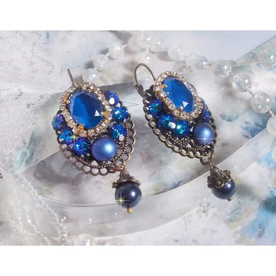 BO Leila avec des cabochons ovales de couleur Royal Blue à laquelle s’ajoute des cabochons ronds, perles nacrées et fleurs. Ils sont tous en Cristal, les dormeuses couleur Bronze sont en Laiton