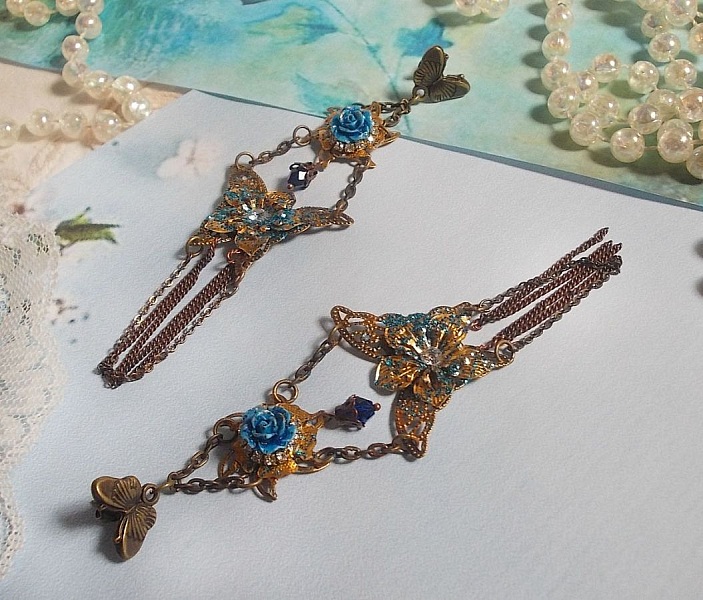 BO Papillons Iris&eacute;s mont&eacute;s sur estampes paillet&eacute;es de Bleu et Bronze, cabochons en forme de rose &agrave; laquelle s&rsquo;ajoute : coupelles fleurs, cha&icirc;ne strass, Zirconiums Cristal et gouttes Cobalt