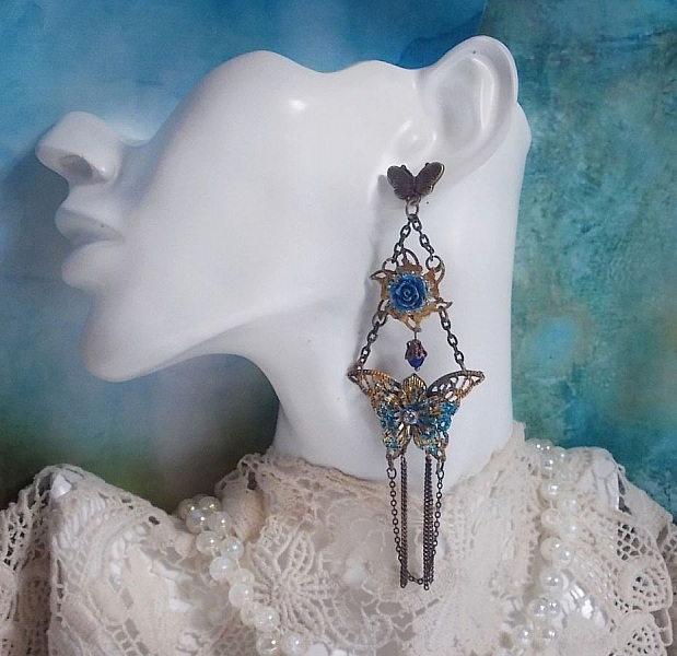 BO Papillons Iris&eacute;s mont&eacute;s sur estampes paillet&eacute;es de Bleu et Bronze, cabochons en forme de rose &agrave; laquelle s&rsquo;ajoute : coupelles fleurs, cha&icirc;ne strass, Zirconiums Cristal et gouttes Cobalt