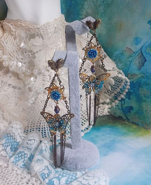 BO Papillons Iris&eacute;s mont&eacute;s sur estampes paillet&eacute;es de Bleu et Bronze, cabochons en forme de rose &agrave; laquelle s&rsquo;ajoute : coupelles fleurs, cha&icirc;ne strass, Zirconiums Cristal et gouttes Cobalt