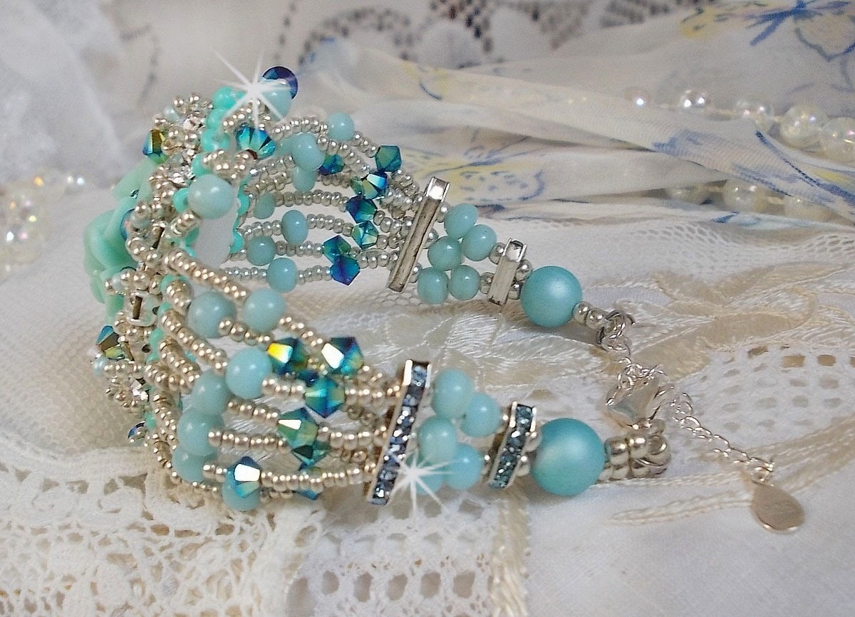 Bracelet Blue Flowers Haute-Couture brodé avec des Cristaux de Swarovski, un cabochon en résine, des perles rondes en satin, des rocailles avec une chaînette et un fermoir en Argent 925/1000