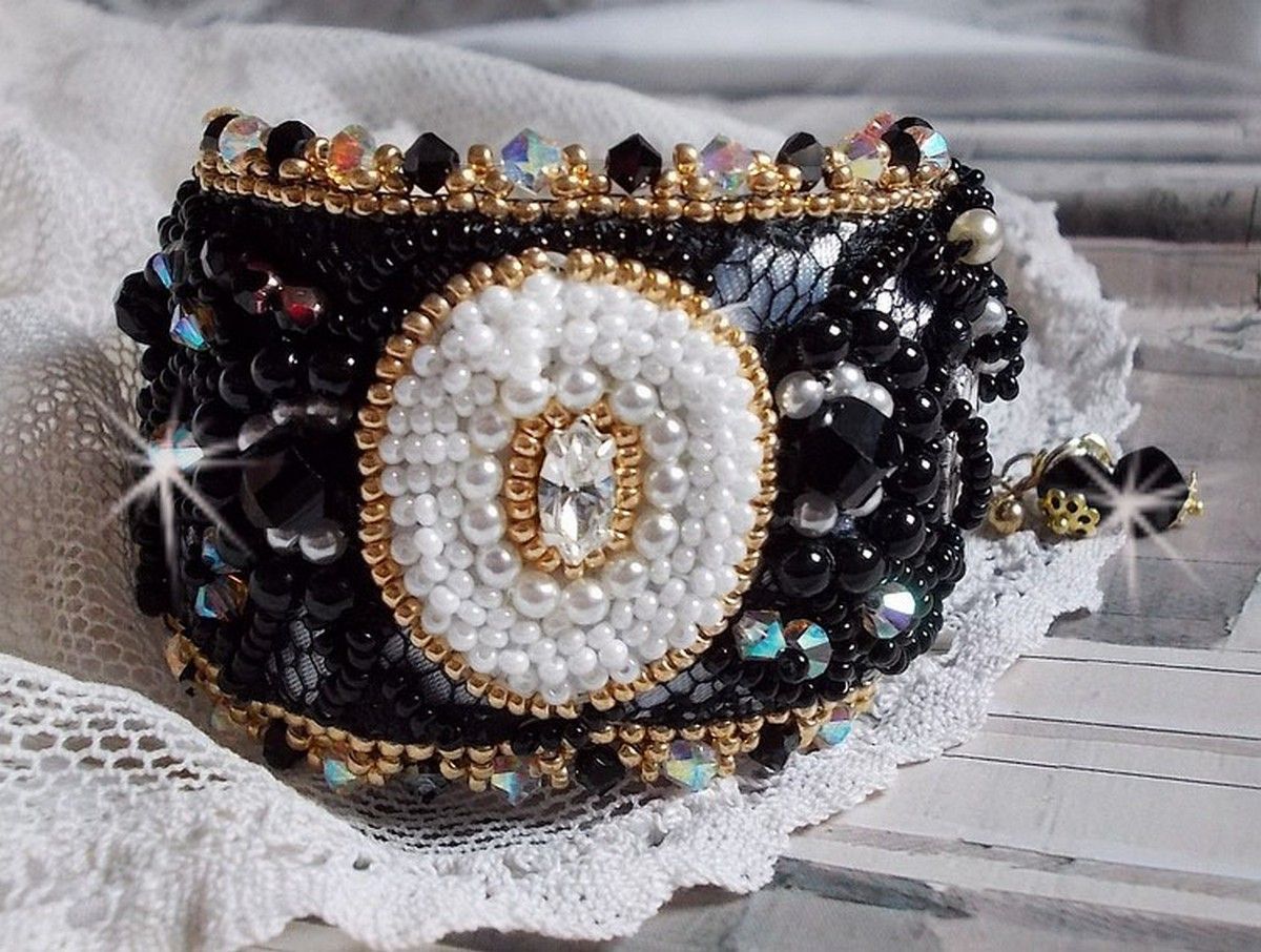 Bracelet Noir Sacré Haute Couture brodé avec des cristaux : navette, hélix Bead,, toupies, breloque fleur strassée,  perles rondes nacrées Verre et rocailles. Les couleurs sont le Noir, Blanc et Doré