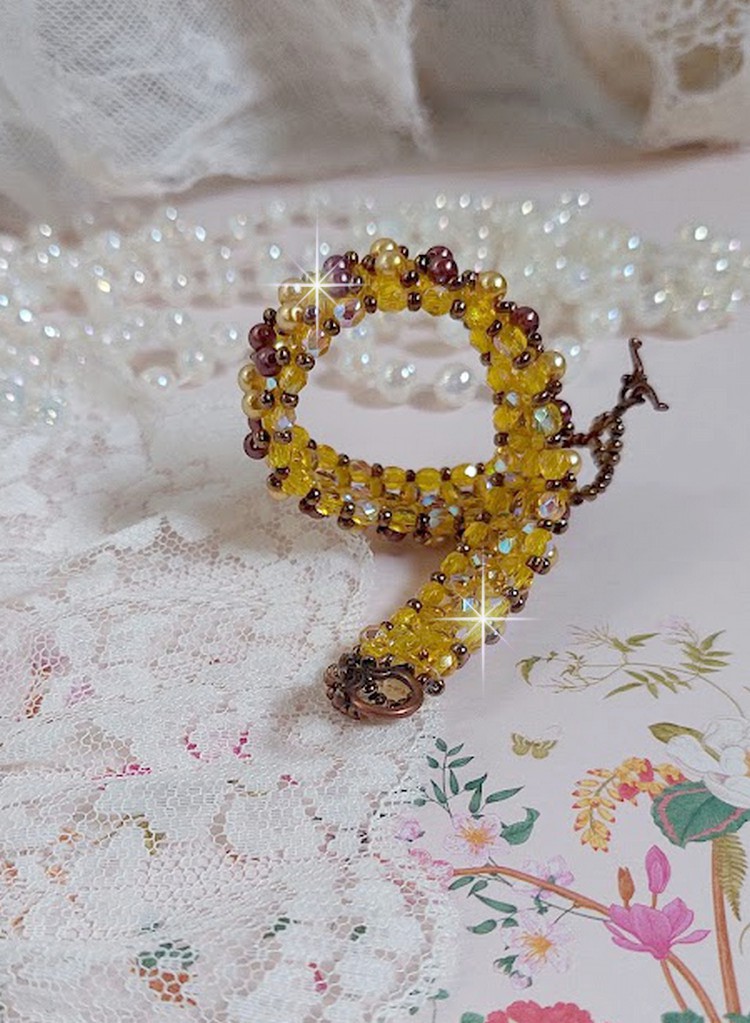 Bracelet Soleil monté avec des facettes en verre de bohème aux couleurs Topaze AB à laquelle s’ajoute des perles rondes nacrées Gold et Maron où elles s’entrelacent avec les rocailles Dorées satinées