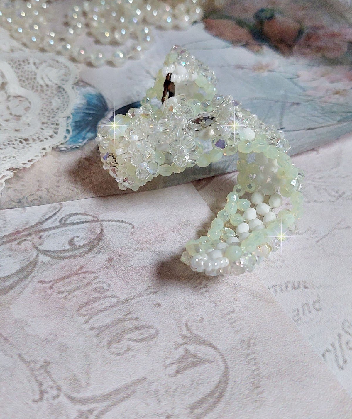 Bracelet Vénus monté avec une cascade de cristaux : toupies et navettes en Cristal AB ainsi que les facettes de couleur Blanche et Beige Opaque de qualité AB, puis perlé de rocailles nacrées 