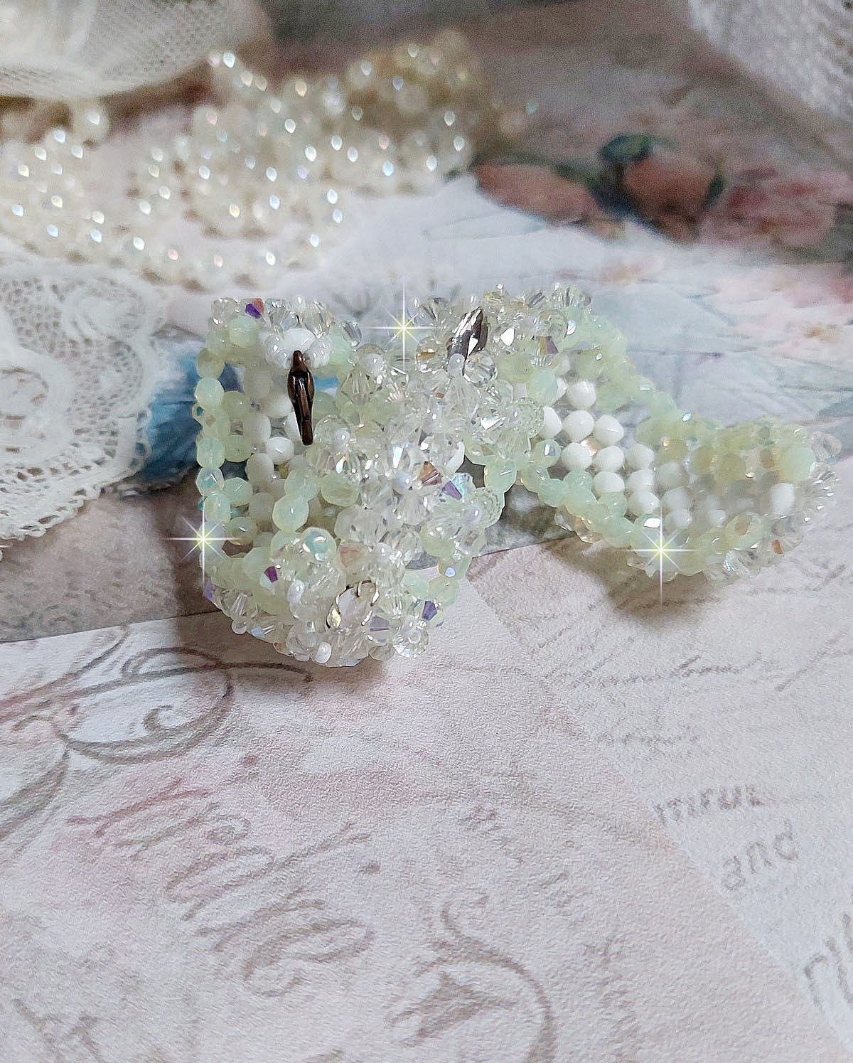 Bracelet V&eacute;nus mont&eacute; avec une cascade de cristaux : toupies et navettes en Cristal AB ainsi que les facettes de couleur Blanche et Beige Opaque de qualit&eacute; AB, puis perl&eacute; de rocailles nacr&eacute;es 