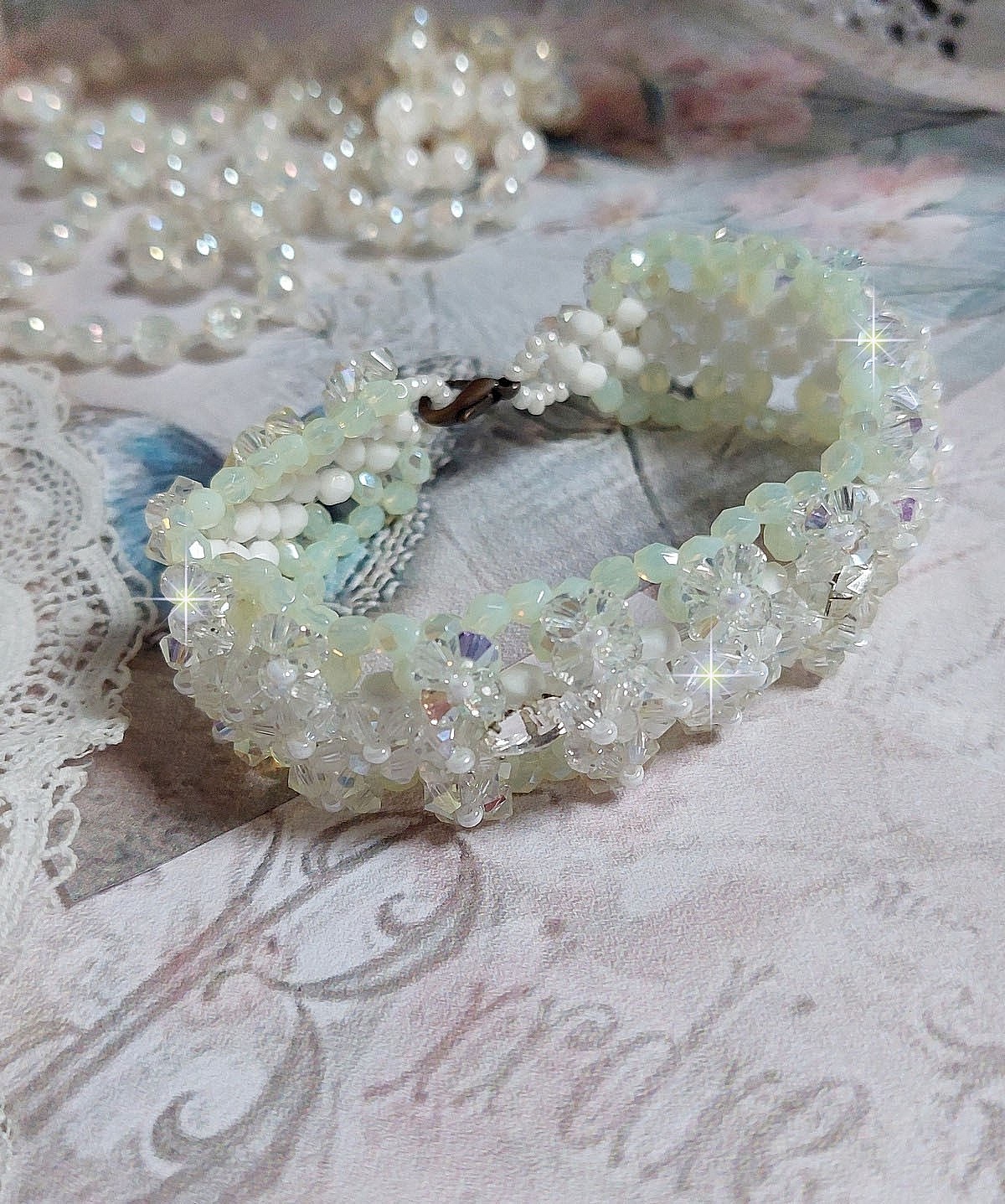 Bracelet V&eacute;nus mont&eacute; avec une cascade de cristaux : toupies et navettes en Cristal AB ainsi que les facettes de couleur Blanche et Beige Opaque de qualit&eacute; AB, puis perl&eacute; de rocailles nacr&eacute;es 