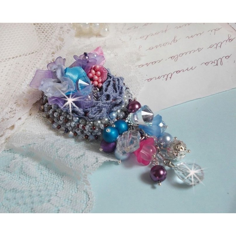 Broche Mademoiselle Bluse Haute Couture brodé avec dentelle Gris perlé, rubans : satin et organza, fleurs en tissu à laquelle s’ajoute des cristaux : perles, navette, toupies et fleurs en résine