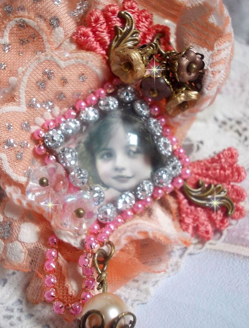 Broche Rustic Rose crée avec un cabochon représentant une jeune fille souriante, de la dentelle Orange strassé et Rose, des cristaux, des perles en verre et des accessoires divers