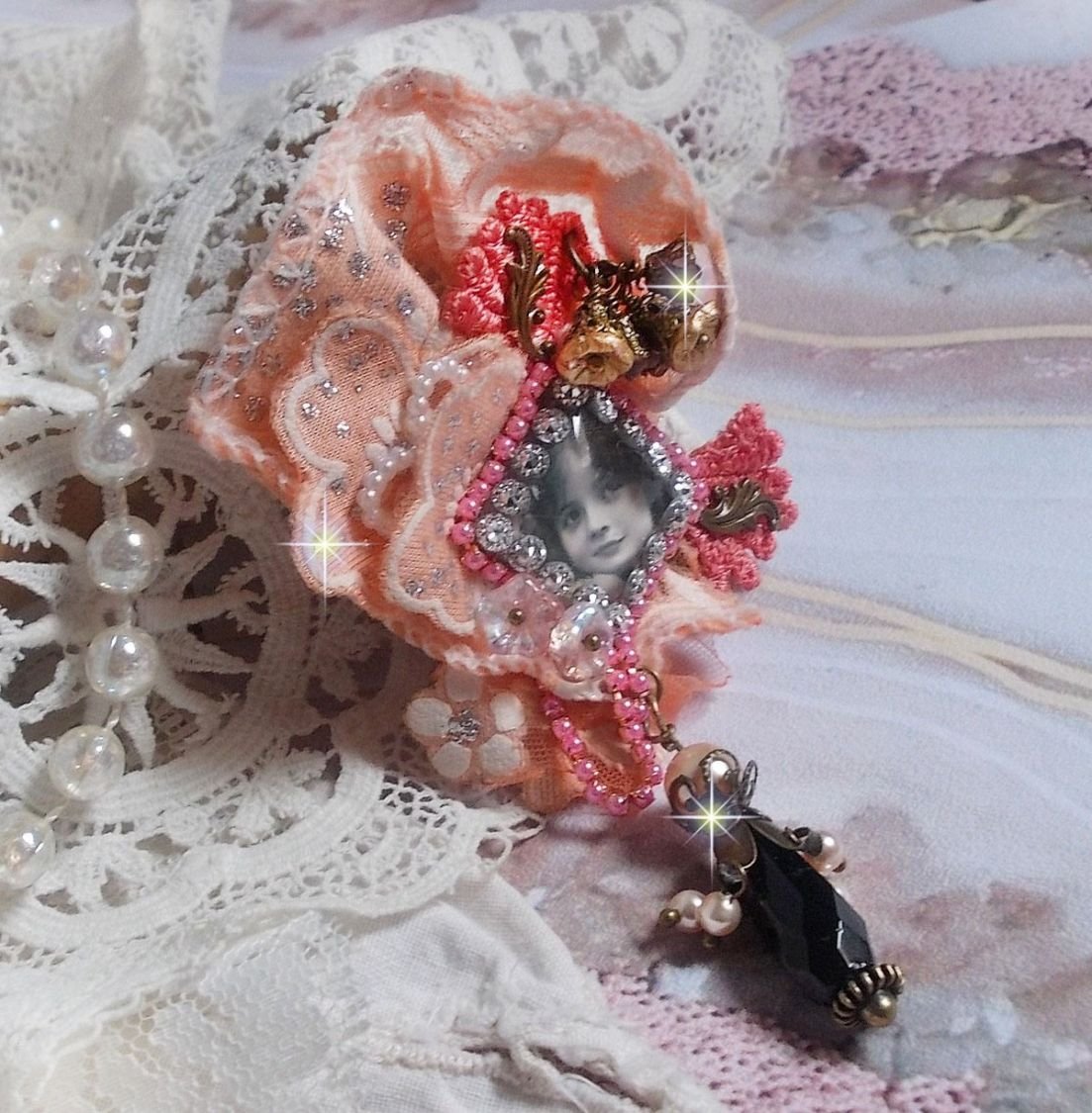 Broche Rustic Rose crée avec un cabochon représentant une jeune fille souriante, de la dentelle Orange strassé et Rose, des cristaux, des perles en verre et des accessoires divers