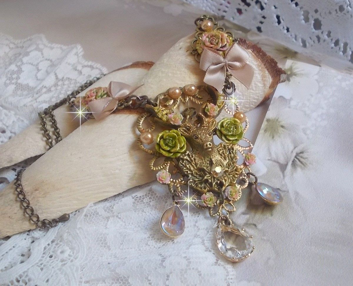 Collier Cerf Fleuri crée avec des cristaux de Swarovski, cabochons en résine, perles en verre, tête de cerf avec bois en métal, pendentif larme en zircon, nœuds en satin et accessoires en laiton 