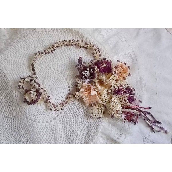 Collier Les Floralies sur une base Netting, j&rsquo;ai r&eacute;alis&eacute; &agrave; l&rsquo;aiguille un bouquet de fleurs et feuilles en rocailles &agrave; laquelle s&rsquo;ajoute des Sugilites. Aux couleurs Ivoire, Am&eacute;thyste, Rose et Purple