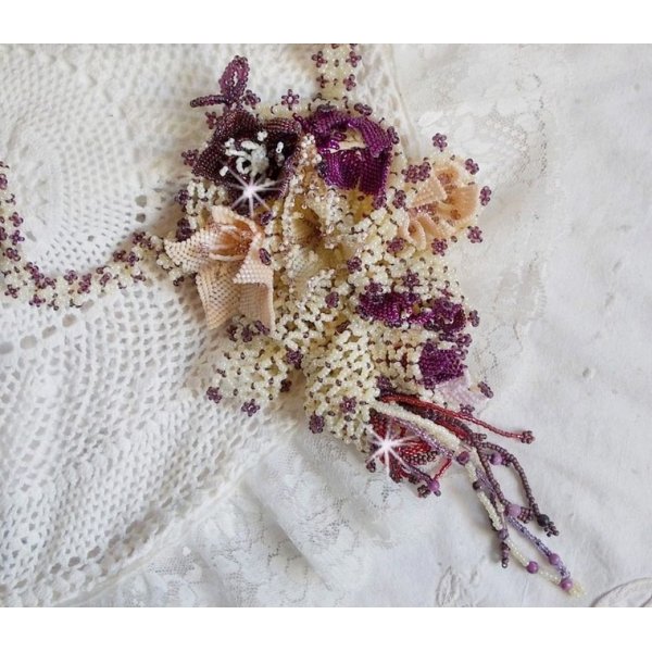 Collier Les Floralies sur une base Netting, j&rsquo;ai r&eacute;alis&eacute; &agrave; l&rsquo;aiguille un bouquet de fleurs et feuilles en rocailles &agrave; laquelle s&rsquo;ajoute des Sugilites. Aux couleurs Ivoire, Am&eacute;thyste, Rose et Purple