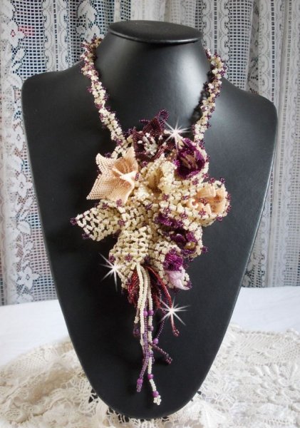 Collier Les Floralies sur une base Netting, j&rsquo;ai r&eacute;alis&eacute; &agrave; l&rsquo;aiguille un bouquet de fleurs et feuilles en rocailles &agrave; laquelle s&rsquo;ajoute des Sugilites. Aux couleurs Ivoire, Am&eacute;thyste, Rose et Purple