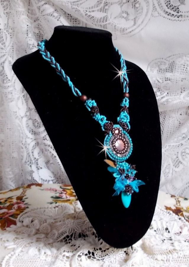 Collier Turquoise Haute Couture au Style Amérindien brodé sur du Cuir avec des cabochons ronds Nacre Acajou et Prune, s’ajoute un cabochon Turquoise. Orné de cristaux, ruban, perles et rocailles 