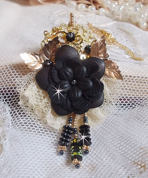 Pendentif Attrapes R&ecirc;ves brod&eacute; avec des fleurs Lucites Noires sur une dentelle Beige et une estampe dor&eacute;e. Les pendants sont des fleurs en cristal avec des rocailles. Mont&eacute; avec une cha&icirc;ne plaqu&eacute; Or
