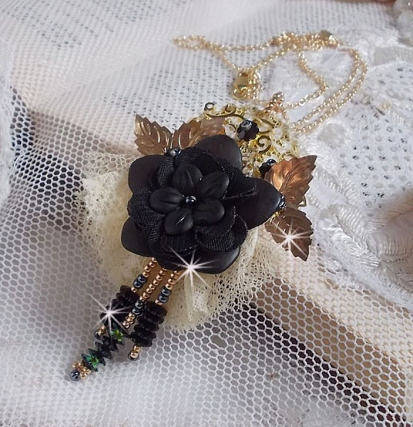 Pendentif Attrapes R&ecirc;ves brod&eacute; avec des fleurs Lucites Noires sur une dentelle Beige et une estampe dor&eacute;e. Les pendants sont des fleurs en cristal avec des rocailles. Mont&eacute; avec une cha&icirc;ne plaqu&eacute; Or