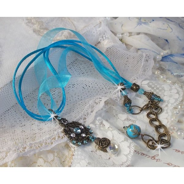 Pendentif Lady in Blue mont&eacute; avec des chandeliers, des cristaux : cabochons, perles rondes et toupies, perles en c&eacute;ramique, cabochons Zirconium, rocailles et rubans. Tout est de couleur Bleu et Bronze